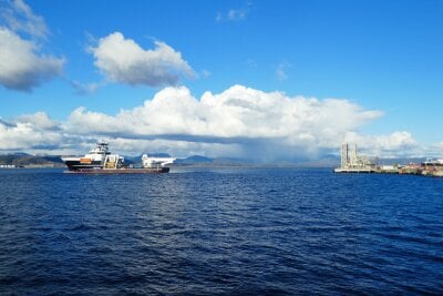 Fjord, blå himmel og skyer. En båt krysser fjorden. Industrianlegg i bakgrunnen.